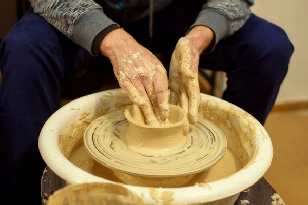 Les mains des potiers hommes se forment par un pot d'argile sur une roue de potiers. Le potier travaille dans un atelier. — Photo