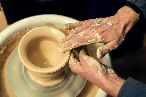 Les mains des potiers hommes se forment par un pot d'argile sur une roue de potiers. Le potier travaille dans un atelier. — Photo