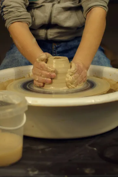 Enfants potiers mains forment par un pot d'argile sur une roue de potiers. Le potier travaille dans un atelier — Photo
