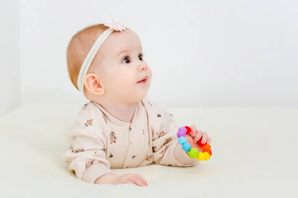 The baby lies and chews a toy for teething. — Stock Photo, Image