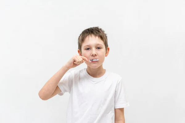 A boy in a white T-shirt is brushing his teeth in the bathroom. — Stock Photo, Image