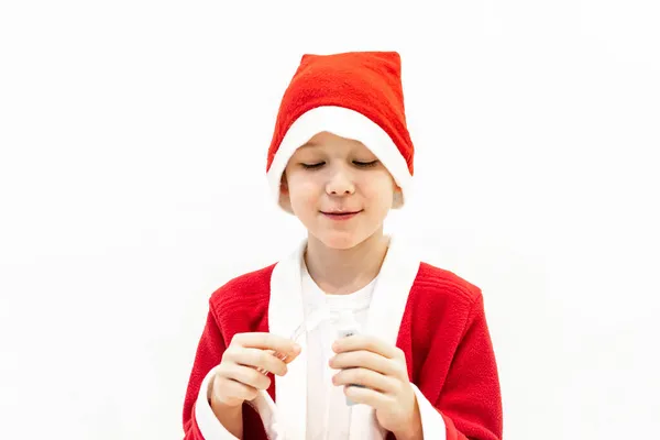 Um menino em um traje de Papai Noel está escovando os dentes no banheiro. — Fotografia de Stock