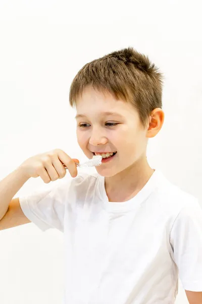 Un chico con una camiseta blanca se cepilla los dientes en el baño.. —  Fotos de Stock