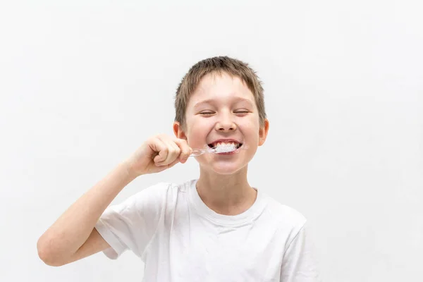 Un chico con una camiseta blanca se cepilla los dientes en el baño.. — Foto de Stock