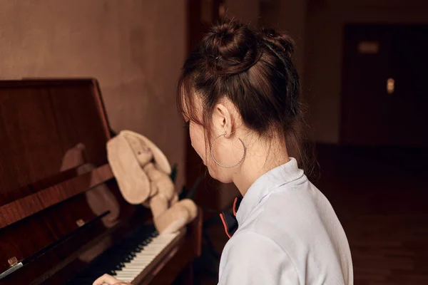 Asian high school student sitting at the piano — Stock Photo, Image