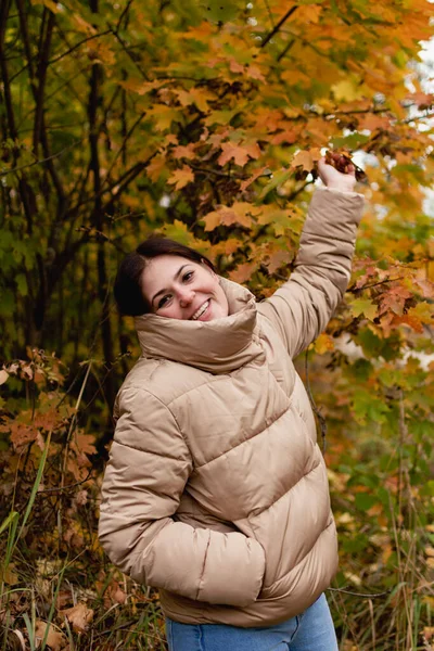 Fröhliche junge Frau in grauer Jacke vor dem Hintergrund einer herbstlichen Landschaft — Stockfoto