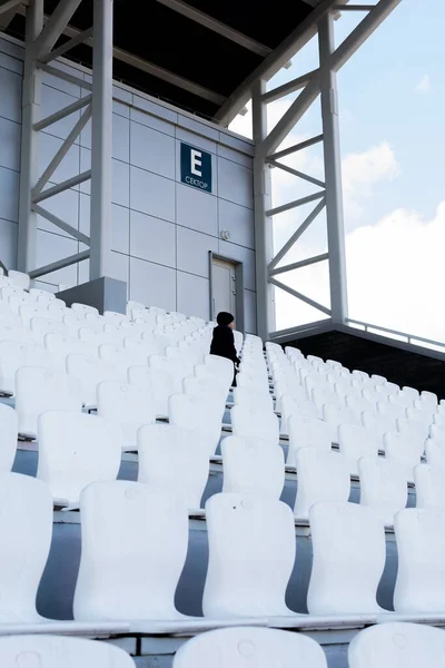 Asientos blancos en el estadio. Niño mira a la distancia —  Fotos de Stock