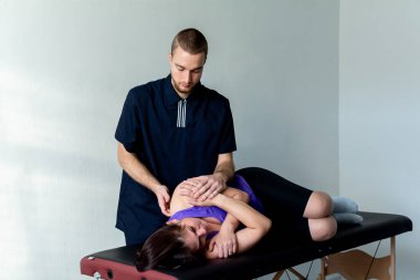 Mavi takım elbiseli bir erkek masaj terapisti bir kadına spor masajı yapar. Sırt ağrısı tedavisi.