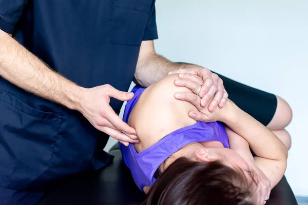 A male massage therapist in a blue suit makes a sports massage to a woman. Back pain treatment. — Stock Photo, Image