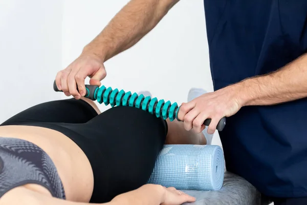 En manlig massage terapeut i blå kostym gör en sport massage till en kvinna. Stockfoto