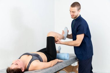 Doktor ya da fizyoterapist, yaralı erkek hasta bacağını tedavi ediyor, klinikte rehabilitasyon tedavisi uyguluyor..