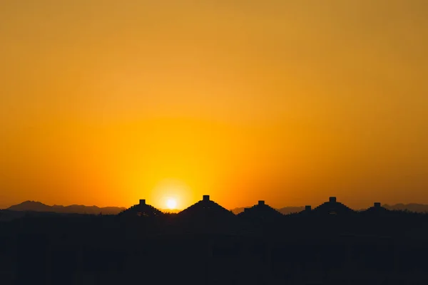 Majestatyczny zmierzch w tropikach. Goden zachód słońca niebo z pięknymi dachami sylwetki parasole plażowe i góry wieczorem. Ciepłe pomarańczowe kolory. Abstrakcyjna natura i tło podróży. Lato w Egipcie. — Zdjęcie stockowe