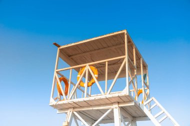 Empty lifeguard house with a bright yellow lifeline on a sunny summer day with blue clear sky. Lifeguard tower on the beach. Colorful travel composition. Safe holiday vacation.