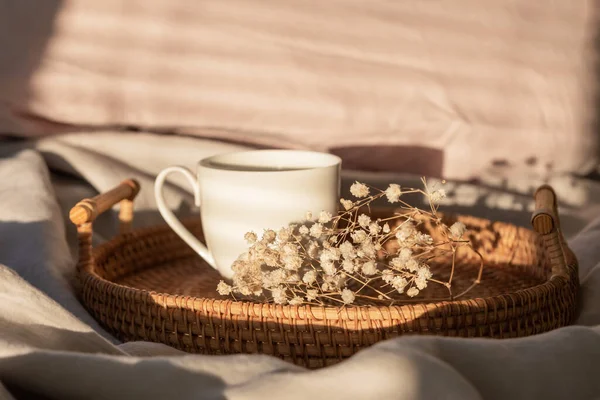 Tasse Kaffee mit Milch auf dem Bett mit grauer Bettwäsche. Kaffee am Morgen. Sonntagseinsamkeit entspannt, Hygge-Stimmung. Minimalistische Komposition mit pastellneutralen Farben. Licht und Schatten. — Stockfoto