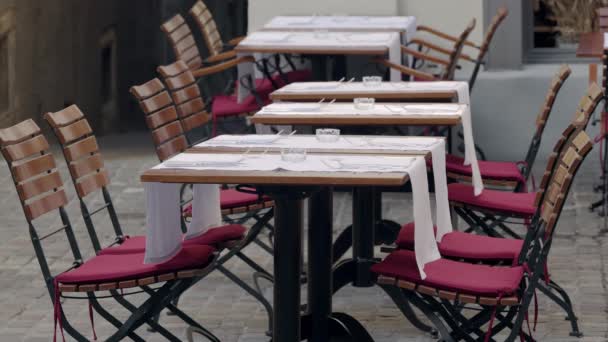 屋外のレストランテラス 空のガラス灰皿のある空の木製のテーブル 赤いシートクッションのある白い食品パッドと椅子 コロナパンデミックのない訪問者 — ストック動画