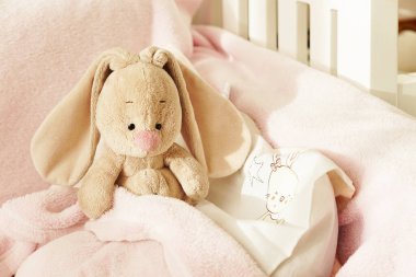 Tatlı, yumuşak, bebeğin yatağında tavşan. Pembe arka planda oyuncak tavşan. Çocuk odası. Hassas bir arka plan. Pembenin tonları.