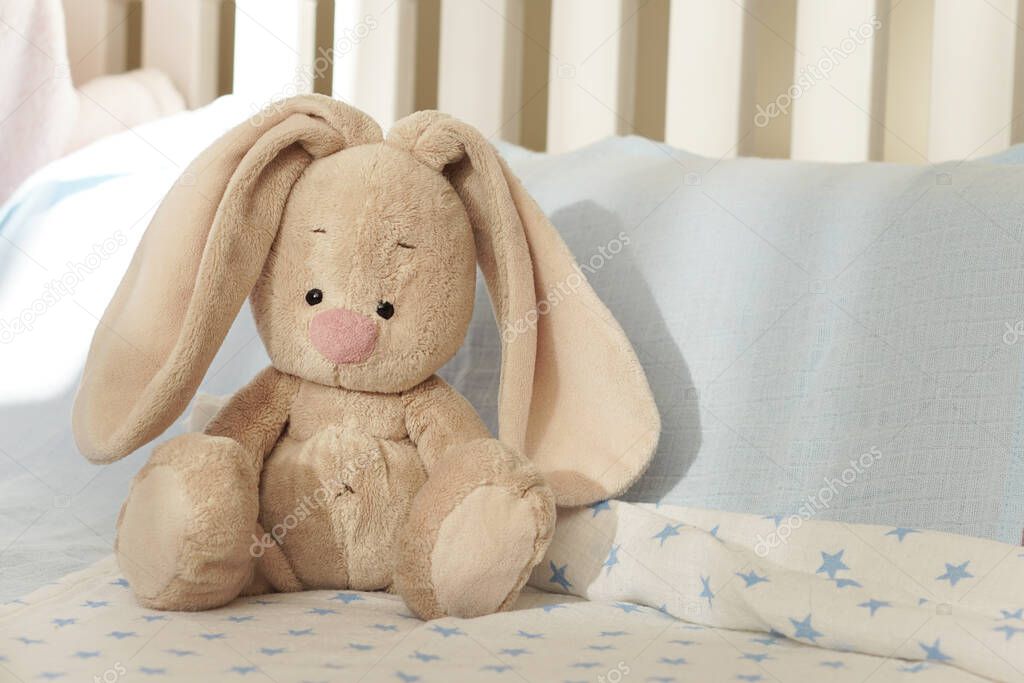 Baby shower. Long-eared hare on a blue background. Toy in the children's room. Children's bed. Favorite toy baby, children's background for birthday greetings.