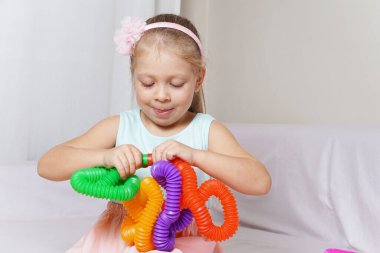 pop tube. anti-stress sensory plastic toy from a tube in the hands of a child. beautiful baby girl playing new modern toy pop tube. trend of 2021. A corrugated tube bent into an interesting metamorphosis shape. Toffee. clipart