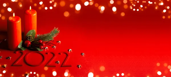 Brett baner grattis Gott nytt år och god jul i rött. Två brinnande ljus med en julgransgren och år 2022. Guldbokeh. — Stockfoto