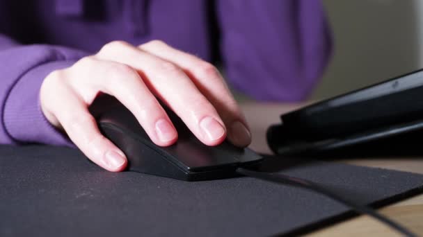 Una mano femenina sostiene un ratón de ordenador, presiona un botón y gira una rueda sobre un fondo púrpura muy Peri de moda. Concepto de trabajo en el ordenador. — Vídeos de Stock
