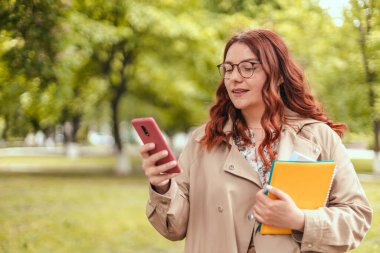 Güzel, mutlu, şık elbiseli kız sokakta cep telefonu kullanıyor.