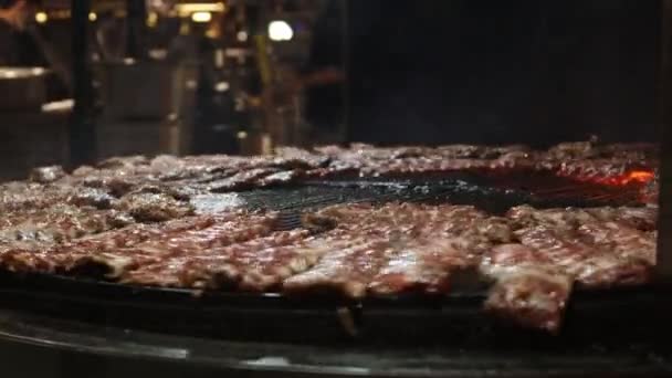 Amerikaans eten smakelijke bbq ribbetjes op grote cirkel vlammende grill in een restaurant. Straat voedsel festival. — Stockvideo