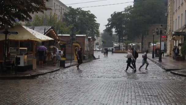 Odessa, Ukrajna, augusztus 23, 2021: Turista autó turistákkal lovagol az esőben a város utcájában. Esős nap a városban, ahol gyalogosok tömegei kelnek át az utcán az esős városban. — Stock videók