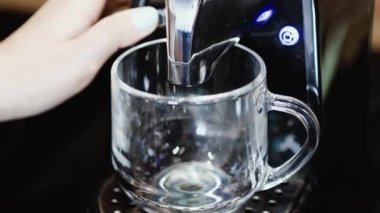 Otomatik kahve makinesinden bardağa taze demlenmiş kahve dökülüyor..