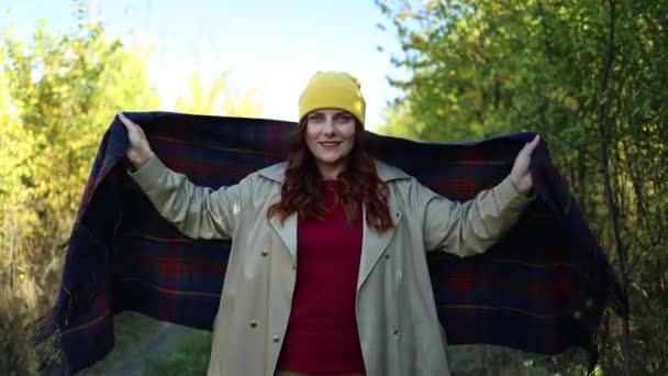 Mooi krullend haar meisje in stijlvolle kleding met een warme wollen plaid wandelen in de stad herfst park — Stockvideo