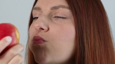 Kafkasyalı genç bir kadın taze kırmızı elma yiyor, taze organik atıştırmalıkların, sağlıklı beslenmenin ve yaşam tarzı konseptinin tadını çıkarıyor.