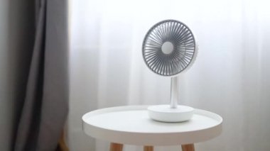 Modern beyaz bir yelpaze odaya serin hava üflüyor. Soğutma sıcaklığı. Vantilatör odanın perdelerinin önüne yerleştirilir..