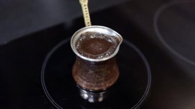 Elektrikli sobanın üzerinde bakır jezve Türk kahvesi yapmak. Geleneksel çömlekte köpük ve kabarcıklar.