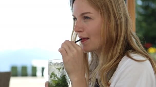 夏のバーで自家製モヒートカクテルを飲む陽気な若い女性の肖像画。暑い晴れた日. — ストック動画