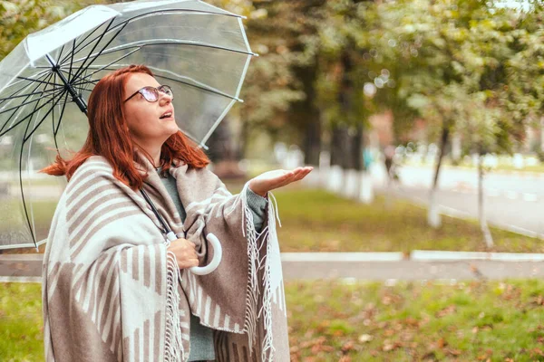 Boldog nő sétál együtt átlátszó esernyővel az őszi városi parkban. Esős idő. — Stock Fotó