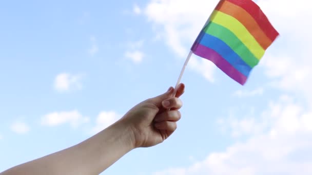 Zbliżenie Ręki Dziewczyny Machającej Małą Tęczową Flagą Jasnoniebieskim Tle Gej — Wideo stockowe