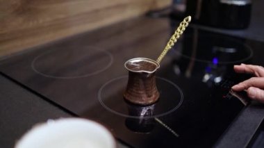 Elektrikli sobanın üzerinde bakır jezve Türk kahvesi yapmak. Geleneksel çömlekte köpük ve kabarcıklar. Tembel sabah