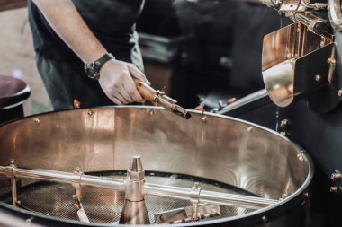 Karanlık ve aromatik kahve çekirdekleri içinde modern bir kavurma makinesi