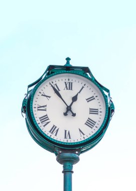 Mavi gökyüzü arka planında yeşil şehir saati. Dikey fotoğraf