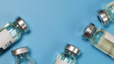 Coronavirus covid-19 deneysel aşı şişeleri laboratuarında kopyalanmış mavi bir plaka üzerinde. Aşılama ve aşılama kavramı