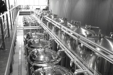 Krom silindirik metal bira tanklarıyla modern el yapımı bira fabrikasının endüstriyel iç mimarisi.