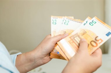 Gri arka planda Euro parası olan kadın eli. İşlem, ödeme, maaş ve bankacılık