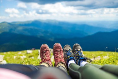 Güneşli bir günde dağın eteğindeki kayanın tepesinde çift bacakları. Tatil ve seyahat. Karpatlar, Ukrayna. Yürüyüşçüler..