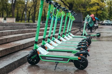 Yağmurlu şehrin göbeğinde darphane kiralayan motorlu scooterlar. Elektrik Şehir Taşımacılığı Konsepti.