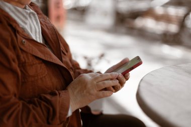 Kadının cep telefonunu kullanırken, şehirdeki kafede cep telefonundan mesajlar okurken görüntüsü kesilmiş.