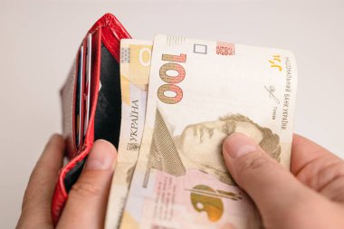 İnsan eli kırmızı cüzdandan Hryvnia banknotları çıkarır, hizmetleri ödemek için, beyaz arka planda krediler