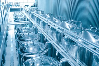 Krom silindirik metal bira tanklarıyla modern el yapımı bira fabrikasının endüstriyel iç mimarisi.