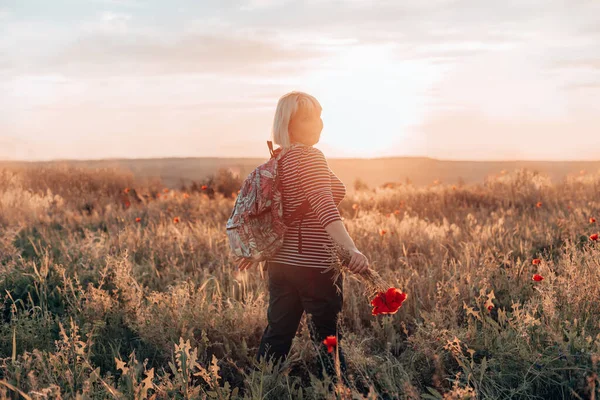 Femme de randonnée debout dans le champ et regardant l'horizon avec un beau ciel au coucher du soleil. Beau paysage, liberté, unité de l'homme et de la nature — Photo