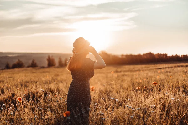 Joyeux beau jeune fille avec un bouquet de pavot dans ses mains dans un champ d'été au coucher du soleil. Tourisme, voyage et mode de vie sain concept. — Photo
