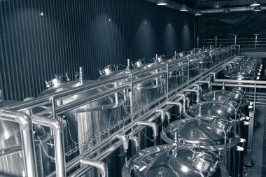 Krom silindirik metal bira tanklarıyla modern el yapımı bira fabrikasının endüstriyel iç mimarisi.