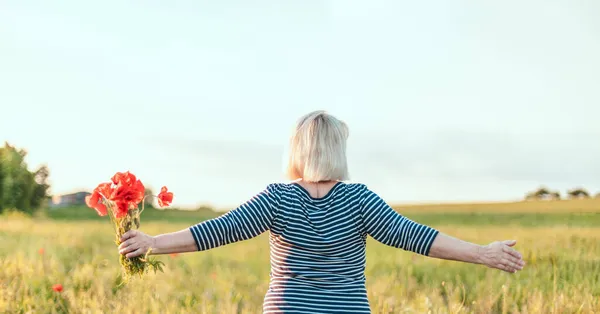 Mulher bonita com cabelo longo mãos para cima em um campo. Jovem feliz desfrutando do sol ao ar livre — Fotografia de Stock